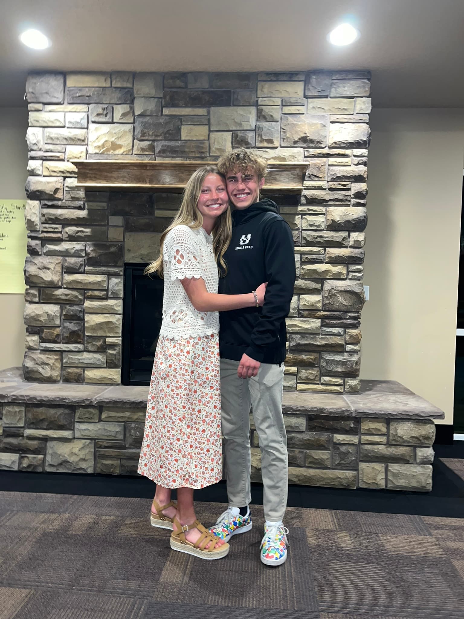 Carson and Courtney hugging by a fireplace